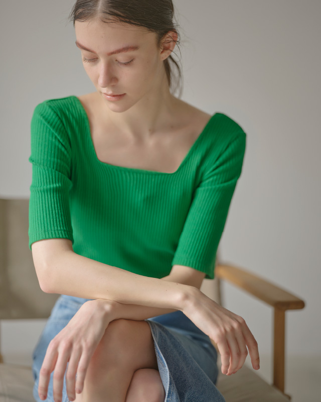 グリーンのハーフスリーブリブトップス（カップ付き）を着用した女性