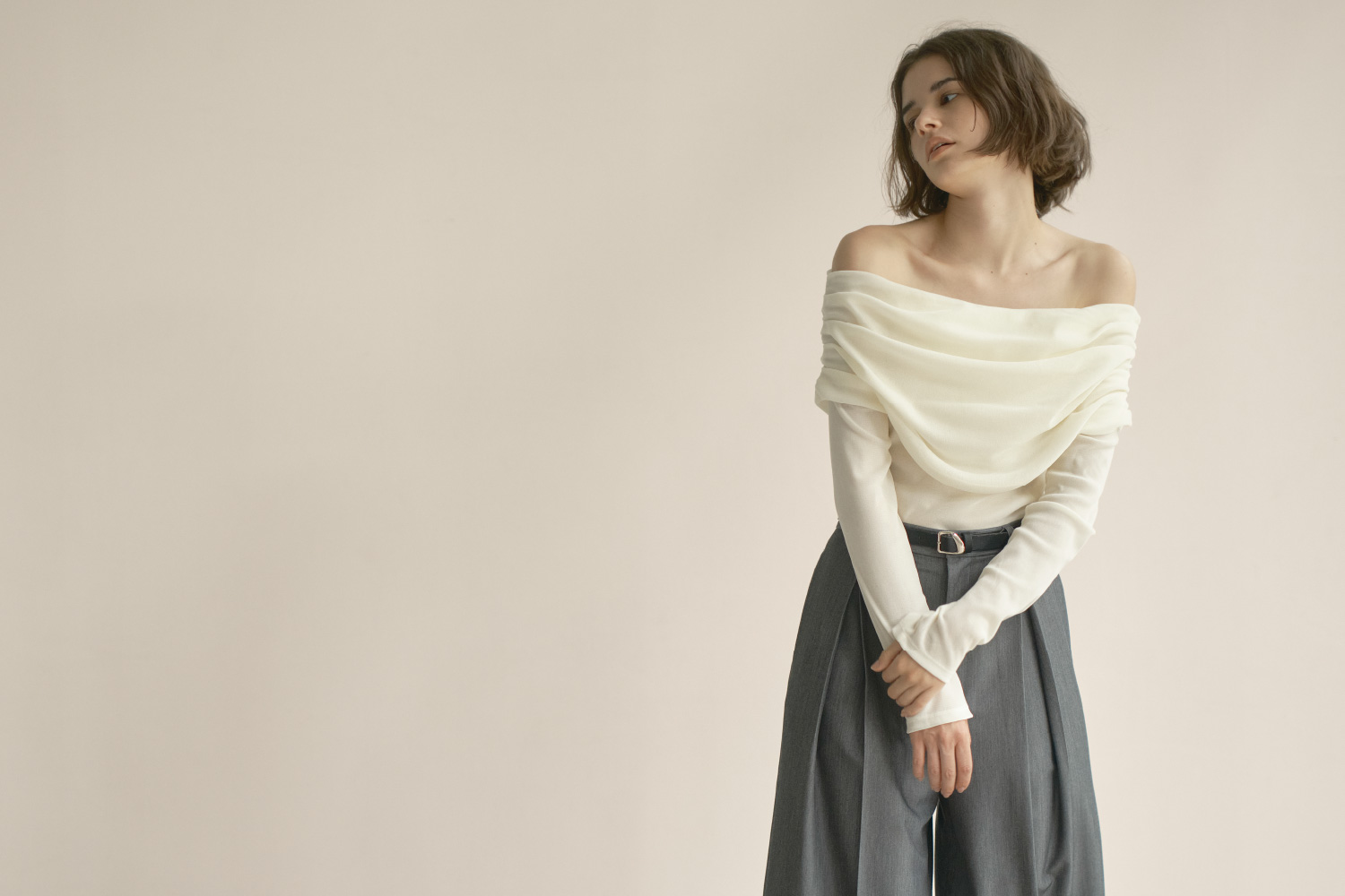 beige色のフロッキーチュールオフショルプルオーバーを着用した女性のイメージ